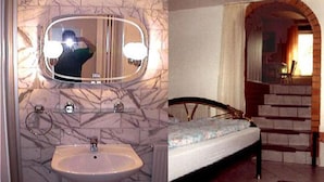 A bathroom with a marble sink, a mirror, and a toilet. The room has a bed with a wooden headboard and a staircase leading to another level. - Pension Münch - Am Anger (Nuenchritz)