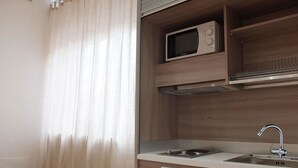 A modern kitchen with a microwave, sink, and wooden cabinets. - Centro Storico Suites (Ferrara)