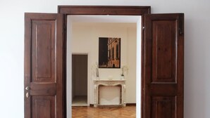 An open wooden door leading to a room with a herringbone patterned floor, a fireplace, and a painting on the wall. - Centro Storico Suites (Ferrara)
