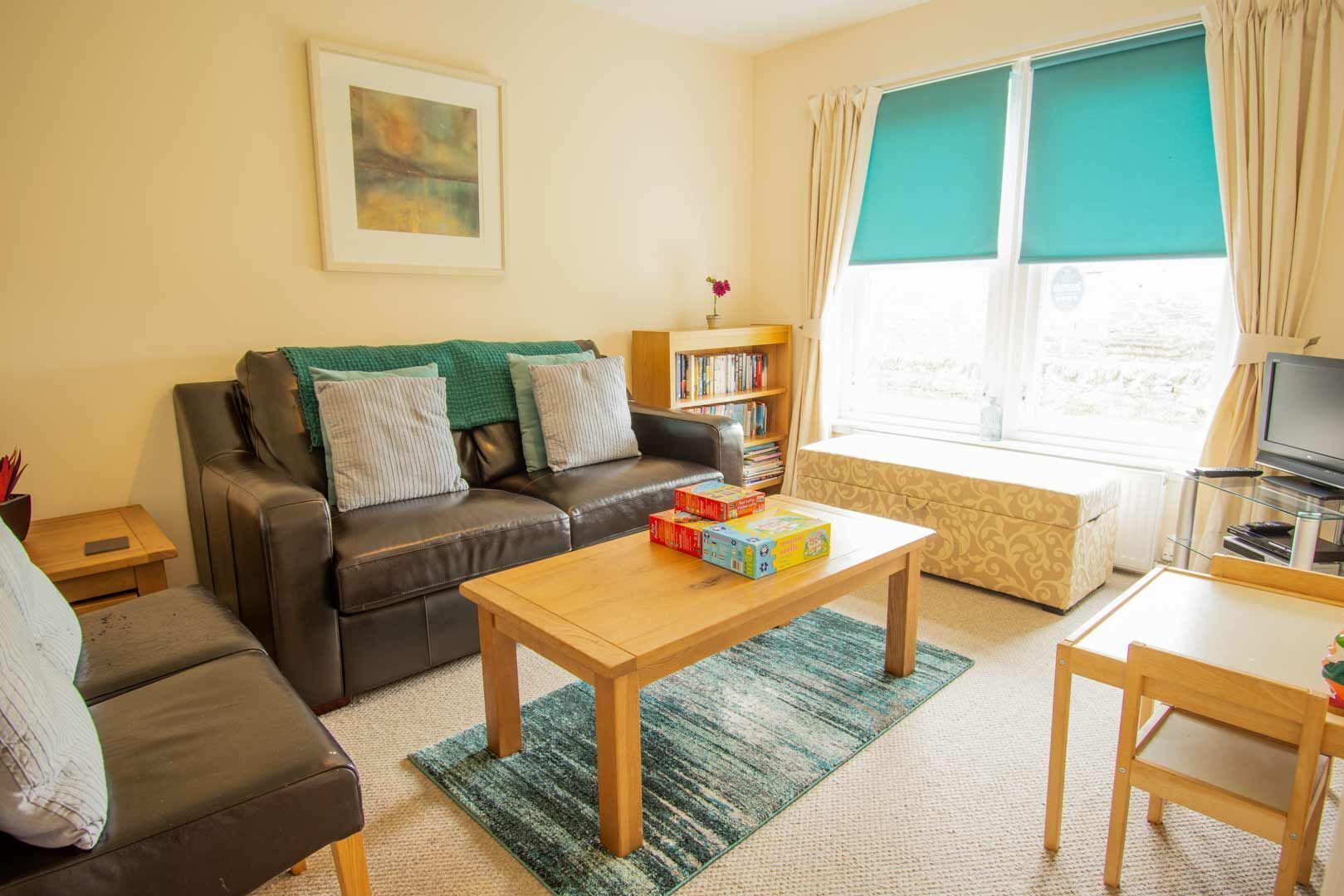A living room with a sofa, a coffee table, a bookshelf, and a television.