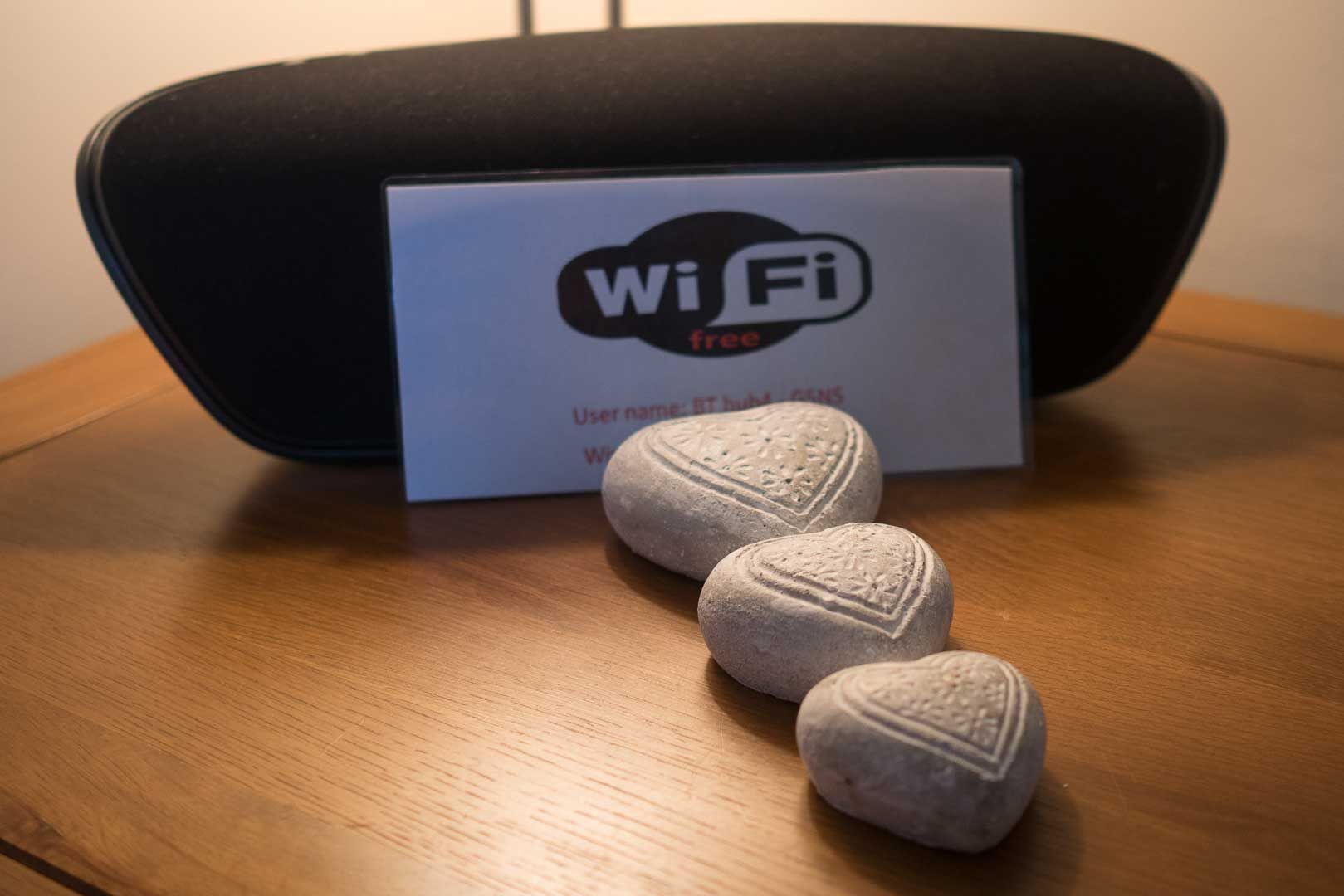 A Wi-Fi sign with a heart-shaped stone on a wooden table.