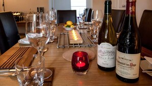 Una mesa de comedor dispuesta con copas de vino, una vela y botellas de vino.