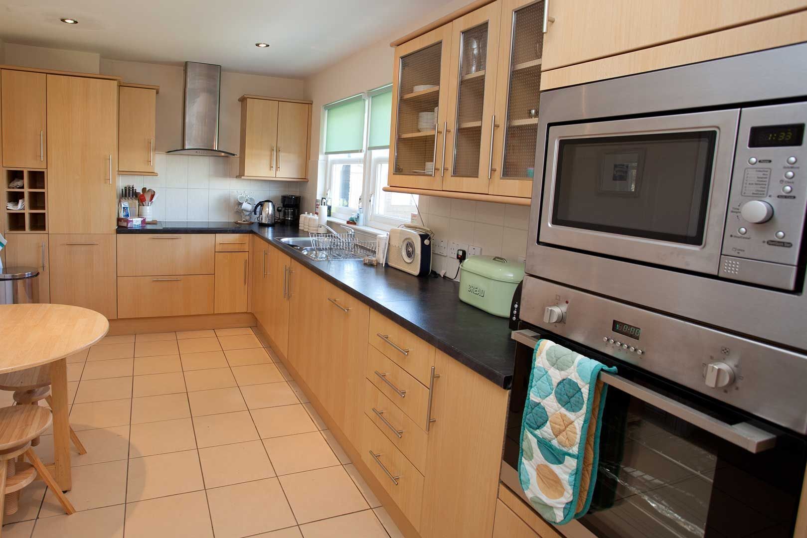 A modern kitchen with wooden cabinets, a stainless steel microwave, and a built-in oven.