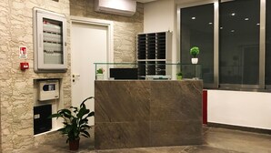 A reception area with a stone wall, a reception desk, a glass display case, and a potted plant.