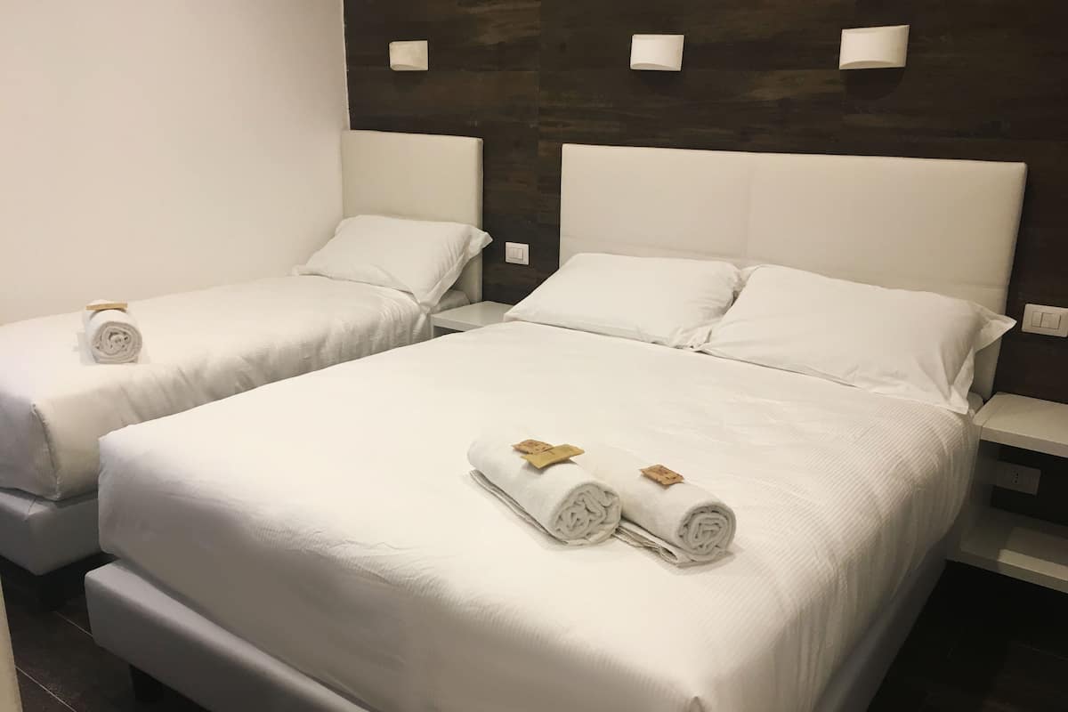 A hotel room with two beds, each with white linens and towels.