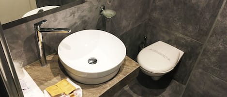 A modern bathroom with a round sink, a toilet, and a mirror.