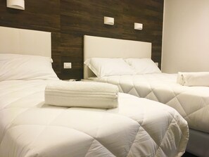 A hotel room with two beds, each with white bedding and a quilted duvet. There are two bedside tables with lamps and a wall-mounted light fixture. - Aurum Firenze (Florence)