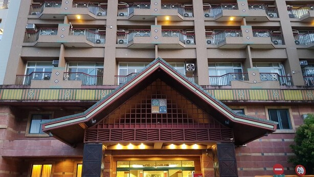 A multi-story hotel with a prominent entrance featuring a decorative archway and a signboard. - Huya Hotel (Taimali)