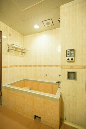 Un baño con una bañera, un perchero para toallas y un dispensador de jabón en la pared.