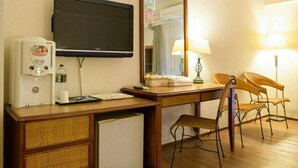 A hotel room with a wooden desk, a television, a coffee maker, a refrigerator, and two chairs. - Huya Hotel (Taimali)