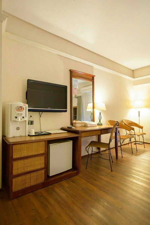 A hotel room with a wooden desk, a television, a coffee maker, a refrigerator, and two chairs. - Huya Hotel (Taimali)