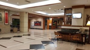 A spacious lobby with a reception desk, seating area, and a large screen displaying a video. - Huya Hotel (Taimali)