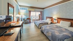 A hotel room with two beds, a desk, a chair, and a balcony with a view. - Huya Hotel (Taimali)