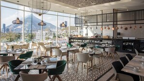 Un restaurante moderno con vistas a la ciudad, grandes ventanales y una variedad de opciones de asientos.