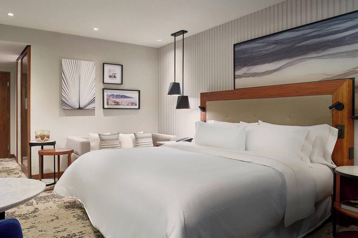 Une chambre d’hôtel avec un grand lit, un canapé, une petite table et un tableau au mur.
