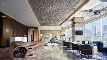 Un lobby de hotel moderno con un mostrador de recepción, zona de estar y grandes ventanales con vistas a la ciudad.