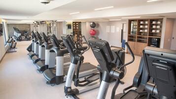 A gym with multiple treadmills and ellipticals, a weight machine area, and a mirrored wall.