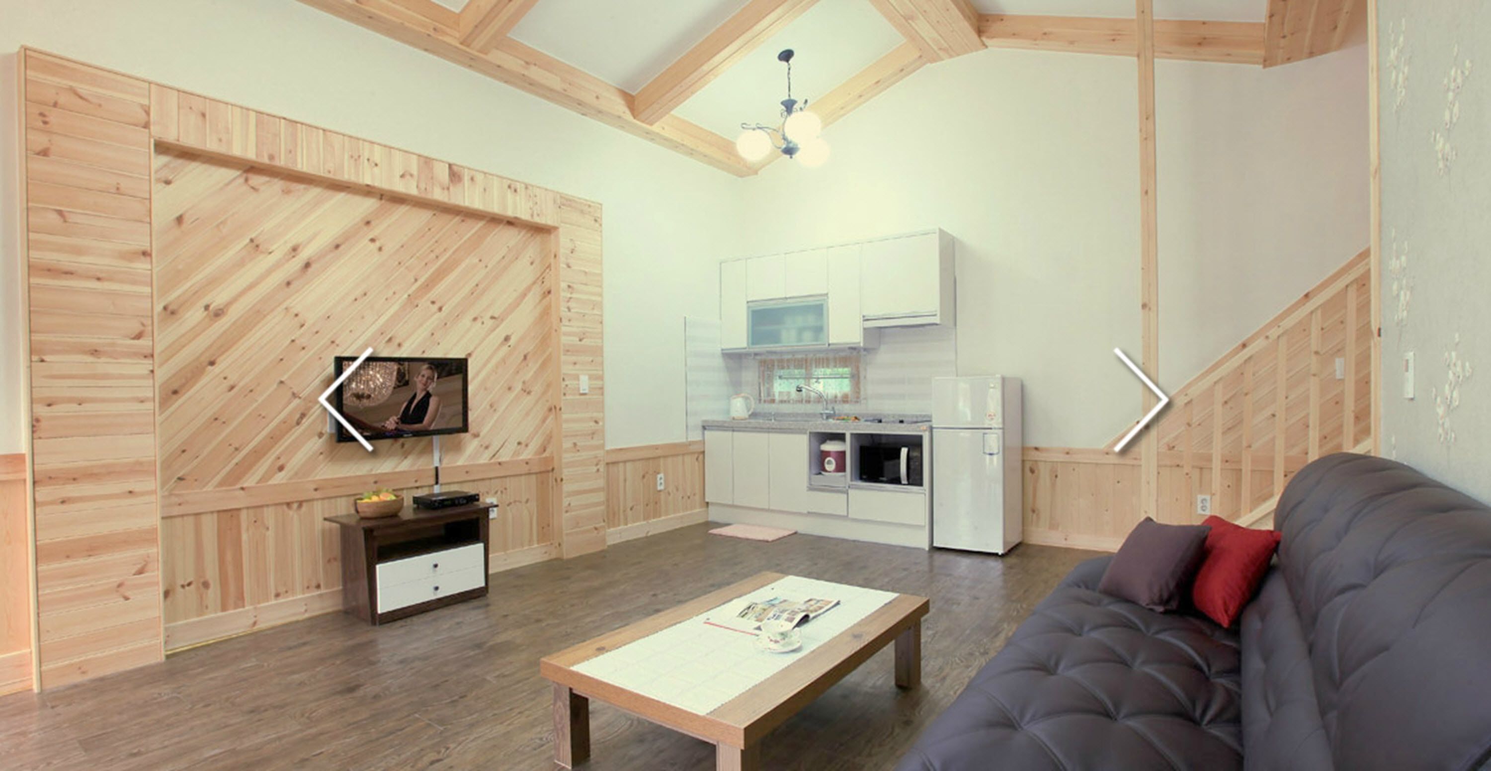 Ein modernes Interieur mit einer Wand in Holzoptik, einer Küchenzeile und einer Sitzecke mit einer Couch.