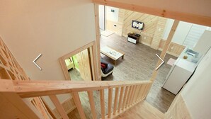 A wooden interior with a dining area, kitchen, and a TV mounted on the wall. - Hansoll Pension (Pyeongchang)