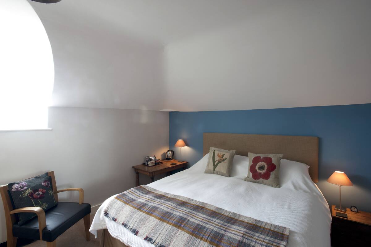 A neatly arranged bedroom with a bed, bedside tables, a chair, and a lamp.