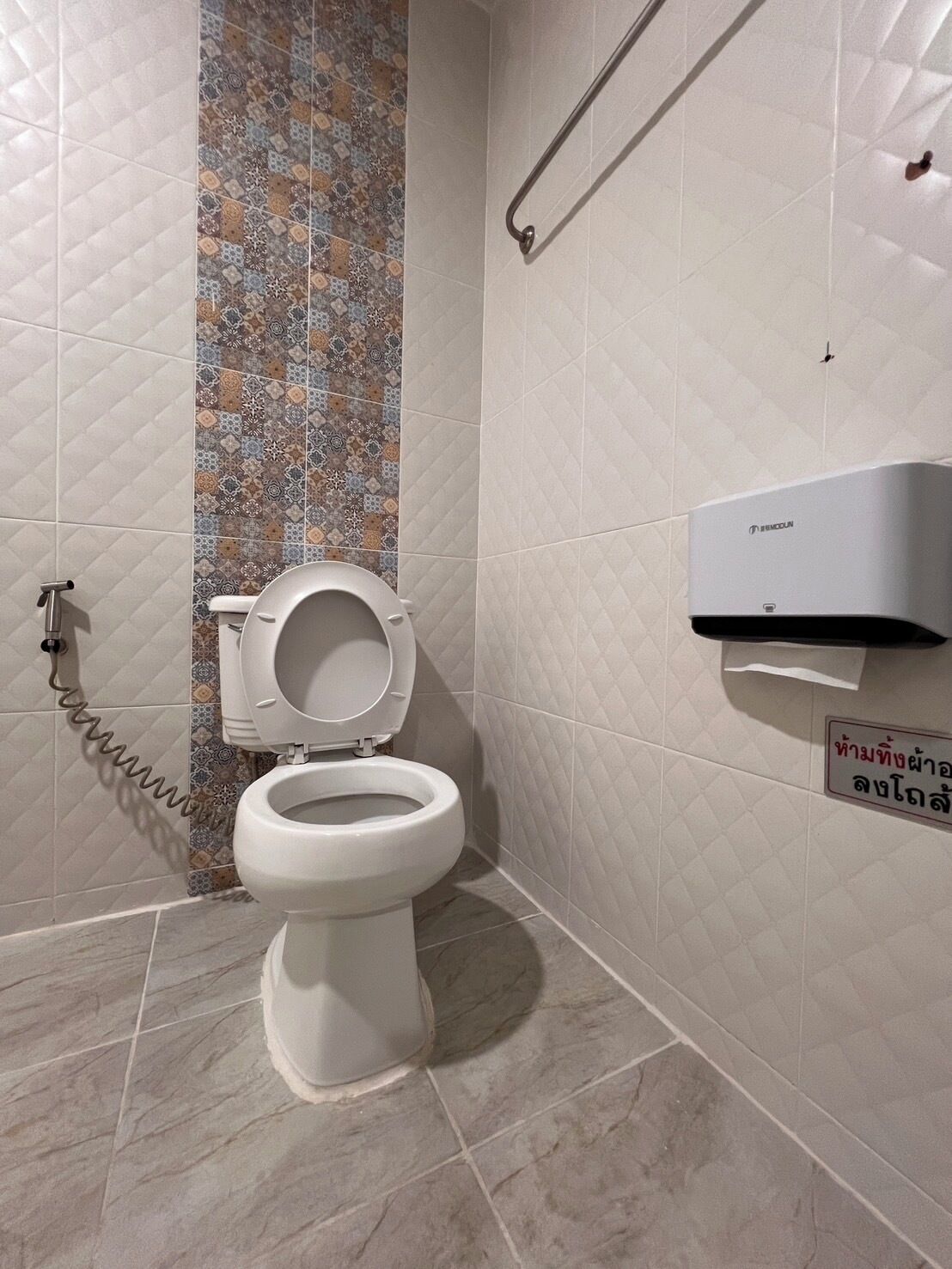 A modern bathroom with a toilet, a hand dryer, and a wall-mounted air purifier.