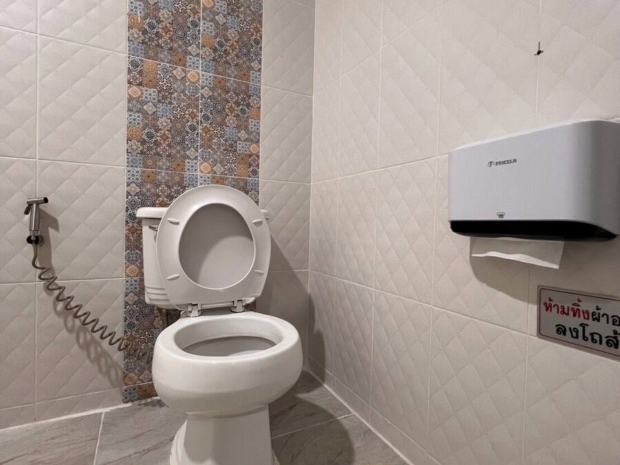 A modern bathroom with a toilet, a hand dryer, and a wall-mounted air purifier.