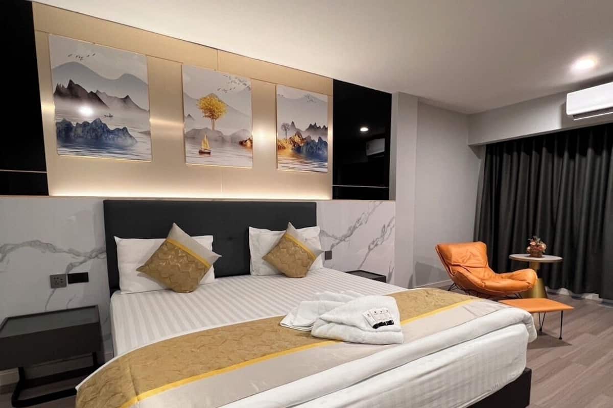 A modern hotel room with a large bed, a nightstand, a chair, and artwork on the wall.