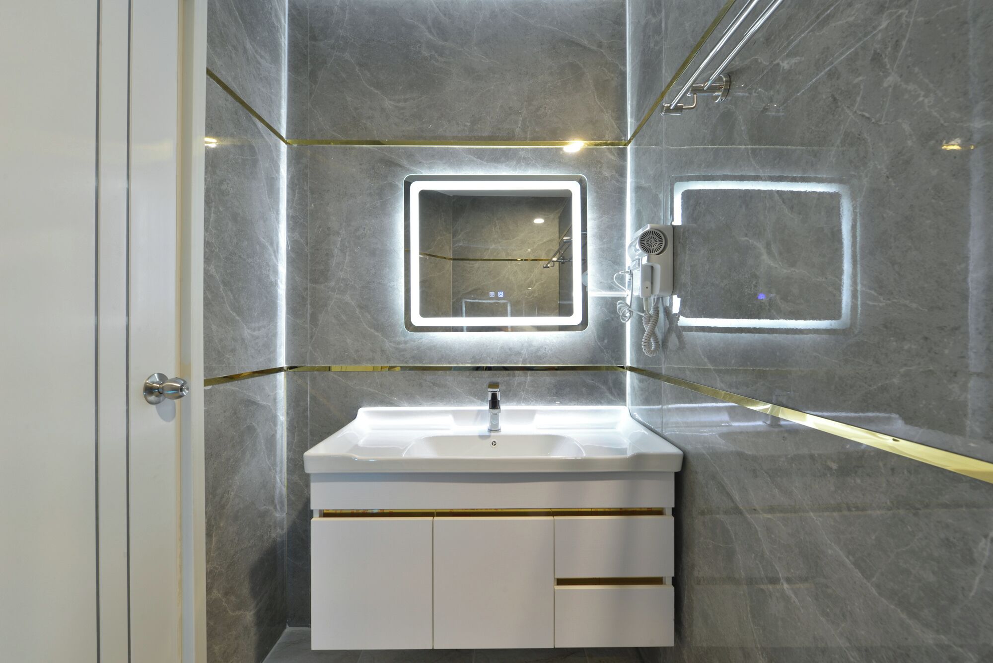 A modern bathroom with a white vanity, two wall-mounted mirrors, and a handheld showerhead.