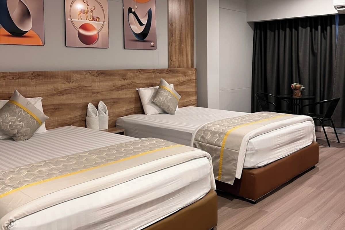A hotel room with two beds, a wooden headboard, and three wall-mounted artworks.