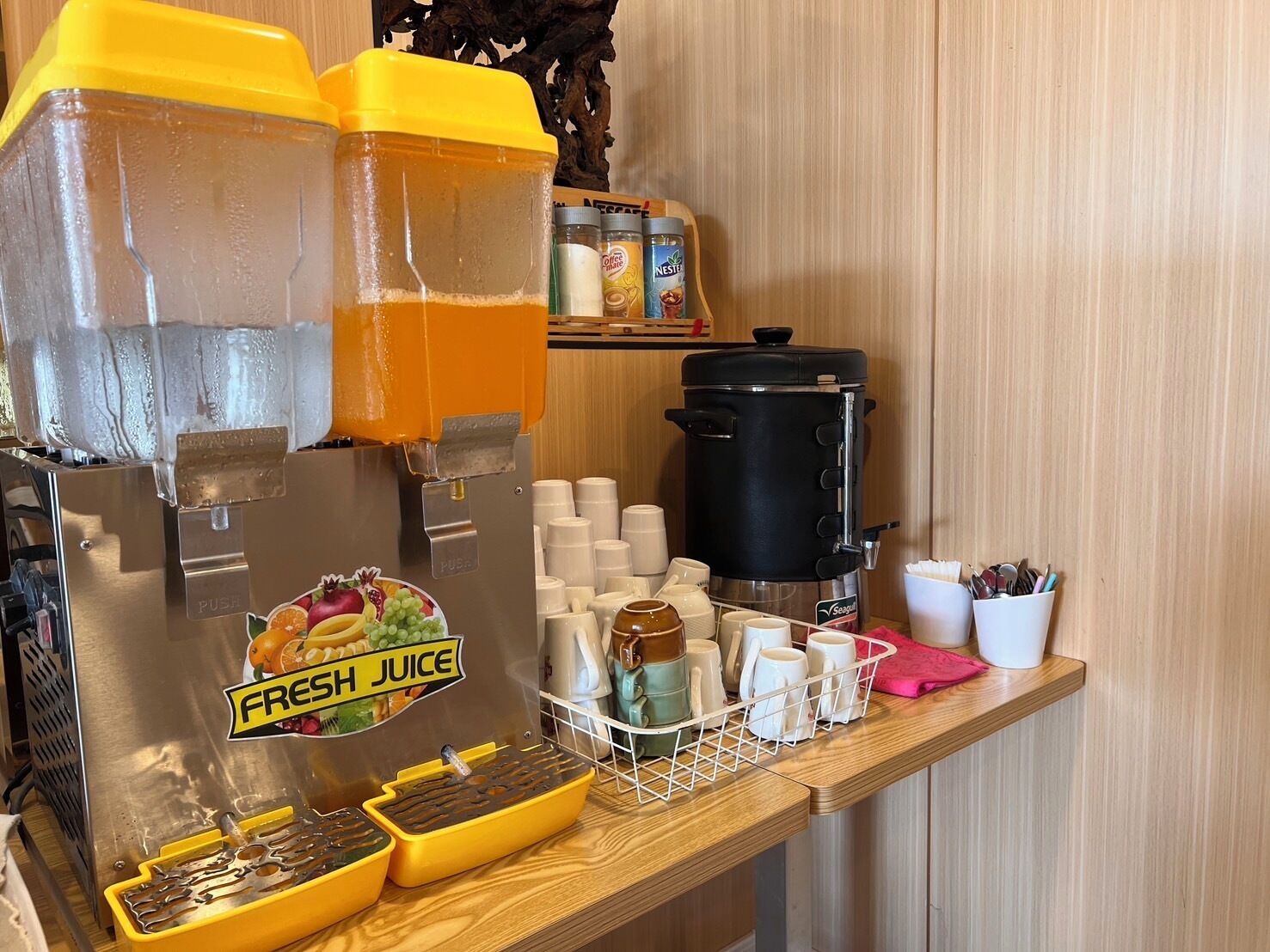 Un bar de zumos con un dispensador de zumos frescos, una máquina de café y un procesador de alimentos.