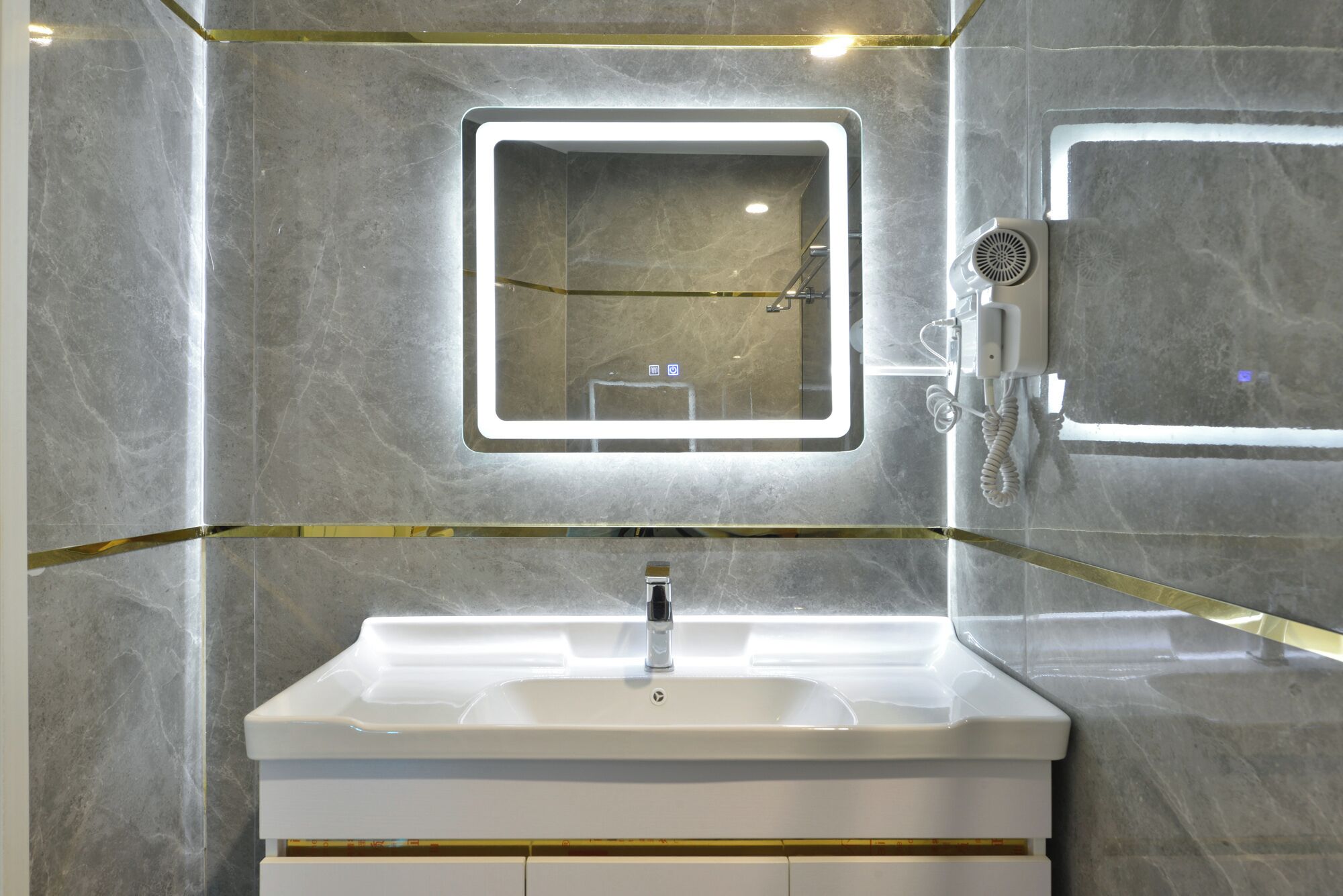 Un baño moderno con un lavamanos blanco, un espejo con luz y un cabezal de ducha de mano.