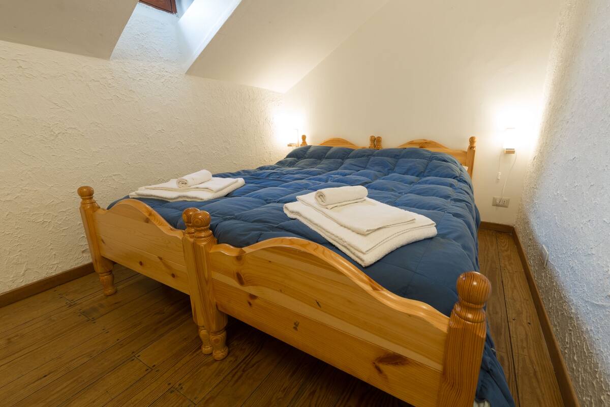 Um quarto com uma cama de madeira, um edredom azul e toalhas dobradas sobre a cama.