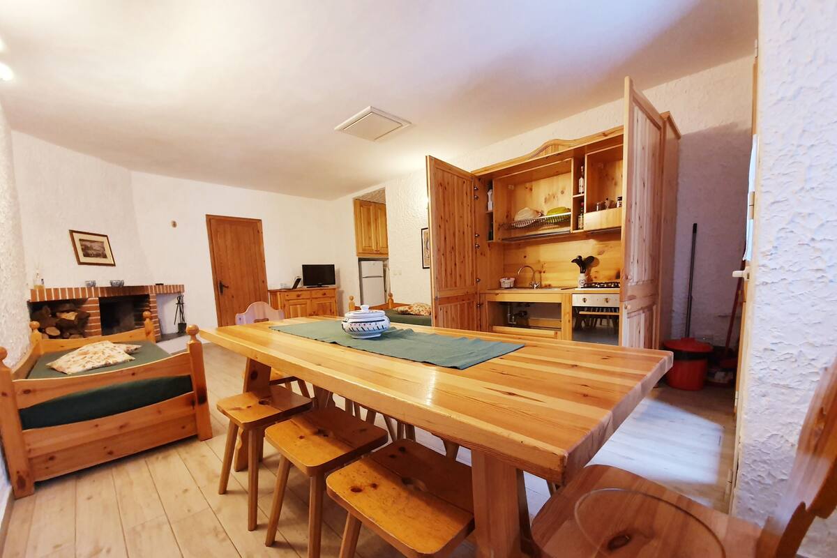 Um interior de madeira acolhedor, com uma mesa de jantar, bancos, um sofá e uma área de cozinha.