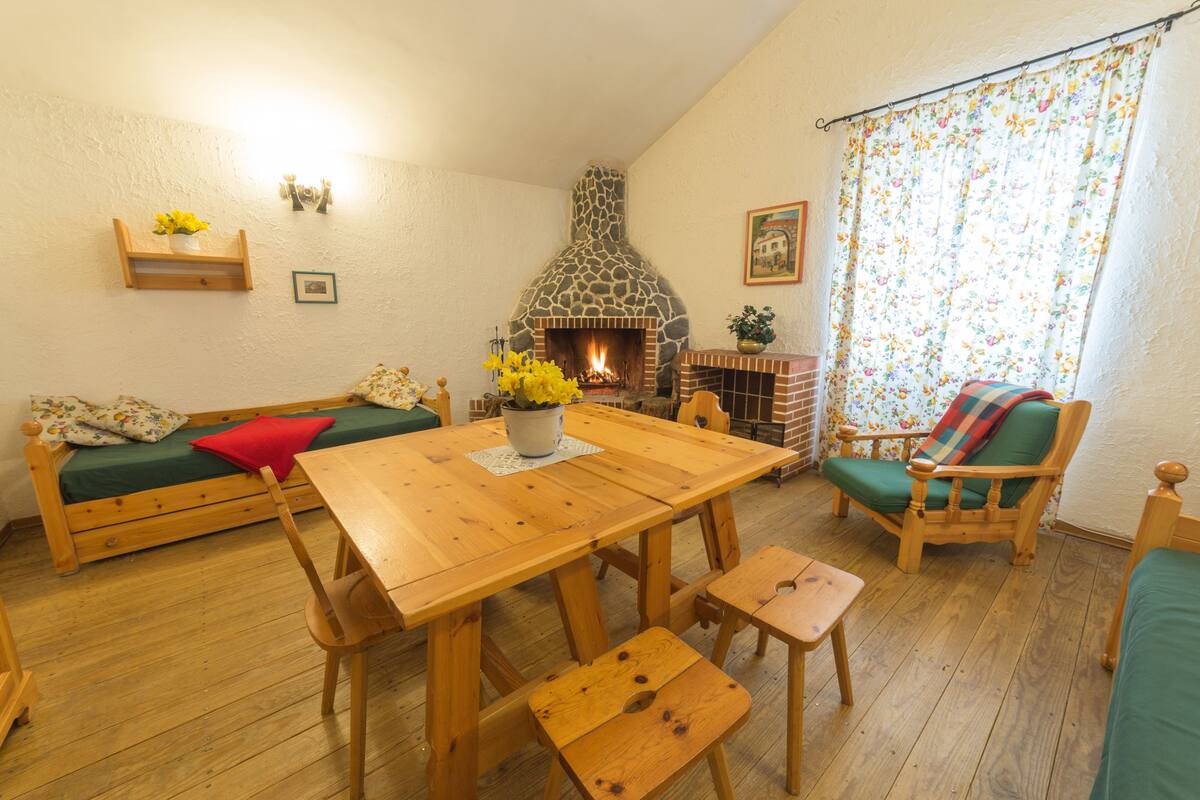Uma sala de estar acolhedora com lareira, móveis de madeira e cortina florida.
