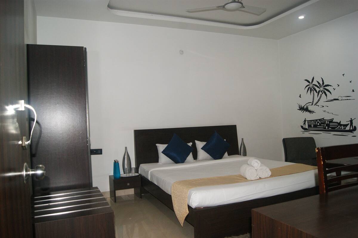 A hotel room with a bed, a nightstand, a chair, and a wall decoration.