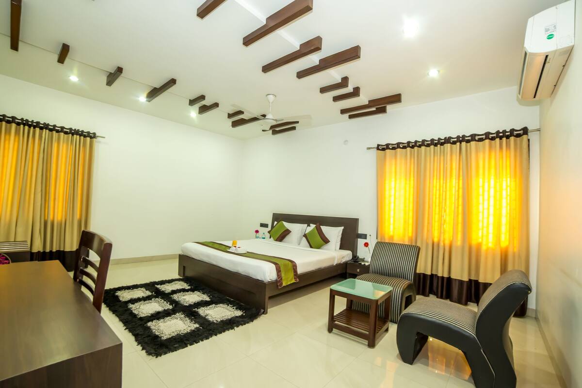 A hotel room with a bed, a desk, a chair, and a small table.