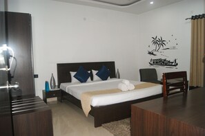 A neatly arranged hotel room with a bed, bedside table, and a desk. - Hill View Serviced Apartments (Hyderabad)