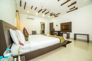 A modern hotel room with a large bed, a desk, a television, and a ceiling fan. - Hill View Serviced Apartments (Hyderabad)