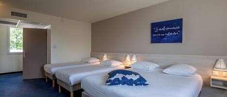 A hotel room with two beds, a wall-mounted quote, and a window with a view of trees.