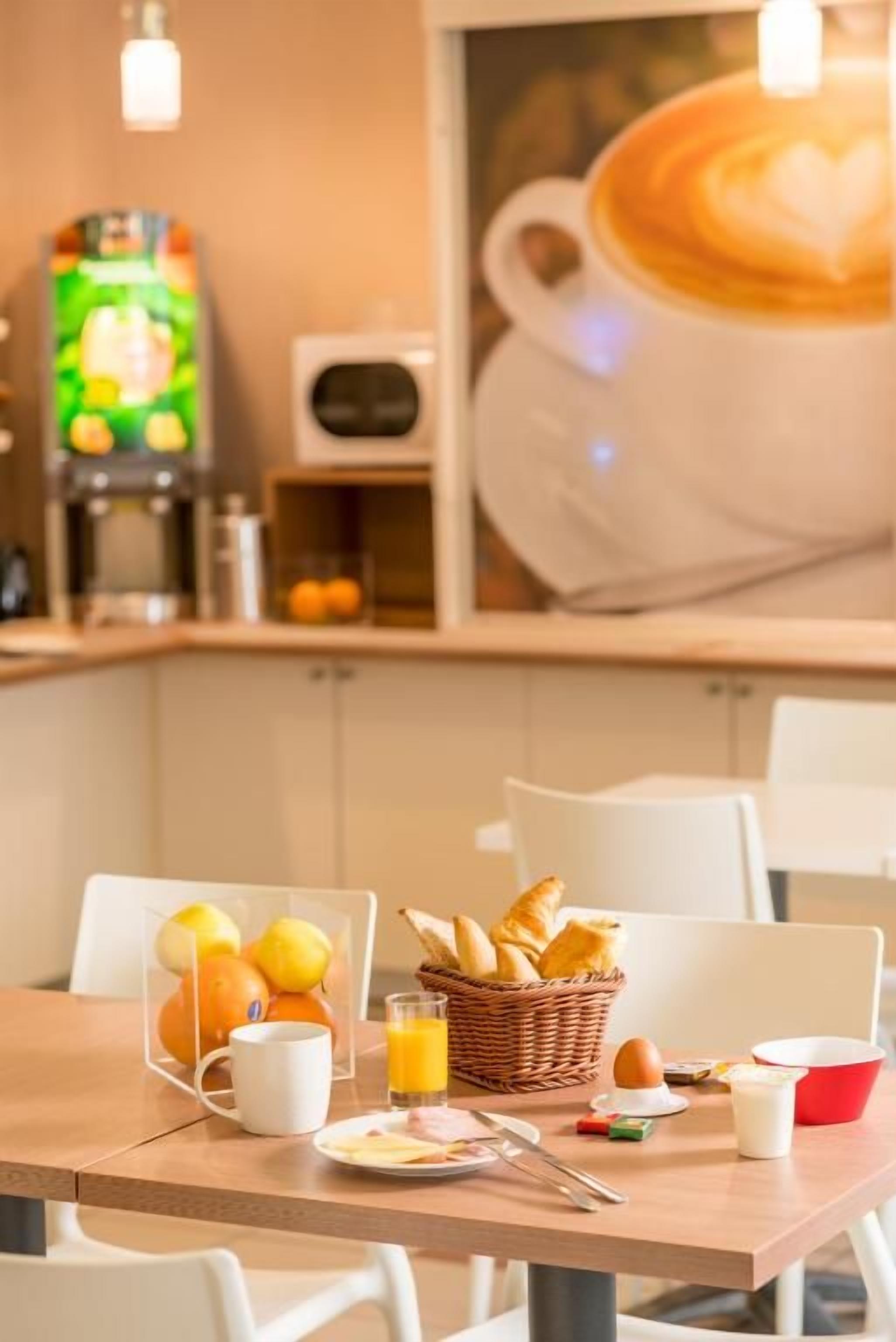 A breakfast table with a basket of croissants, a mug, a plate with eggs, and a glass of orange juice.