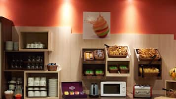 Zona de desayuno tipo bufé con diversos alimentos, un microondas, un tostador y una caja de té Lipton.