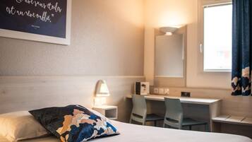 Habitación de hotel con cama, escritorio, silla, lámpara y una pared con una cita.