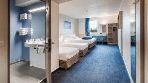 A hotel room with three beds, a bathroom with a sink and towel rack, and a desk with a chair. - ACE Hôtel Toulouse (Cornebarrieu)