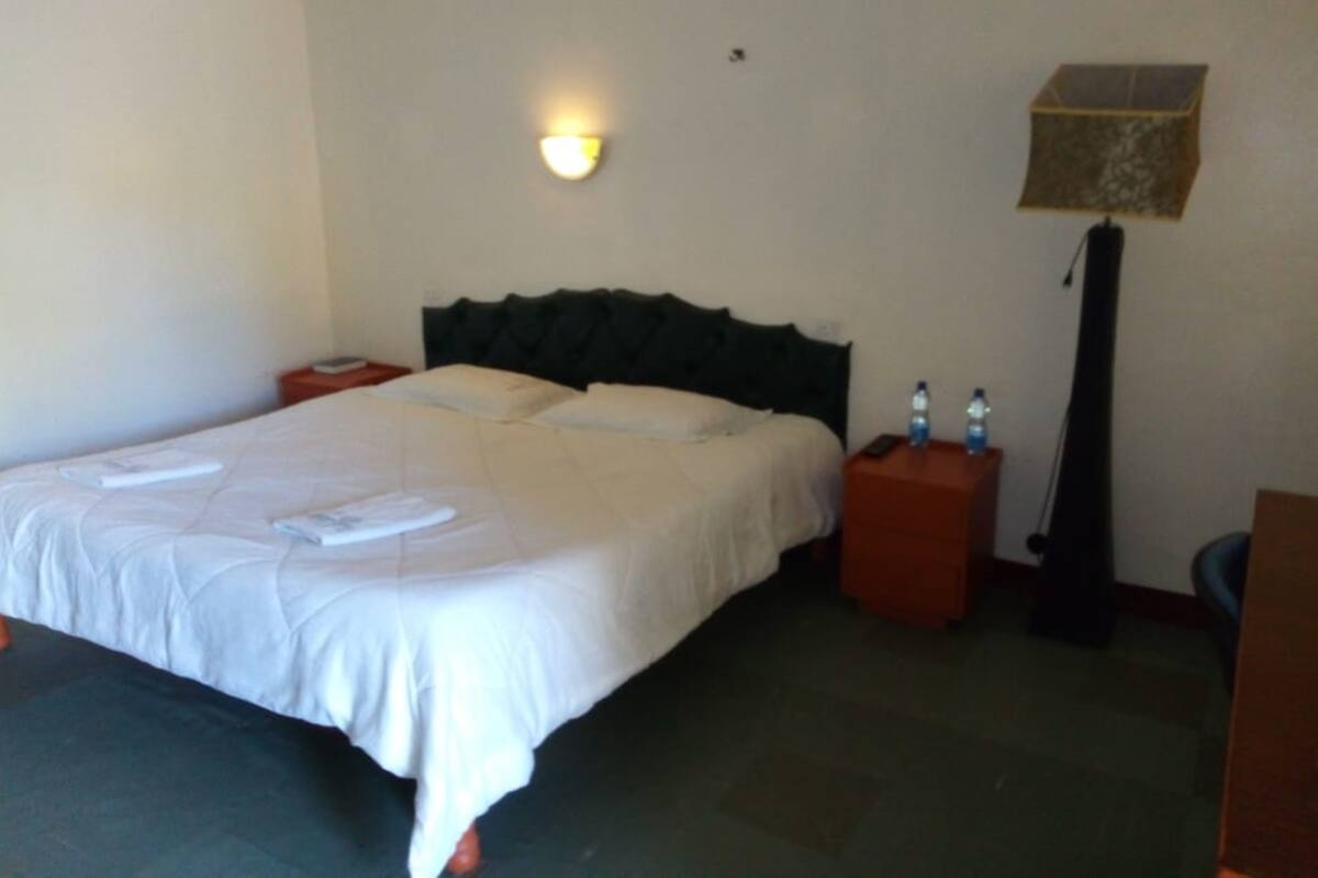 A hotel room with a bed, bedside tables, a lamp, and a nightstand.