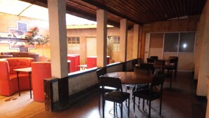A restaurant with a wooden ceiling, red and black chairs, and a large window. - Family Comfort Hotel (Nanyuki)