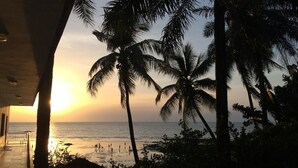 Blick auf einen Strand mit Palmen und einem Sonnenuntergang.