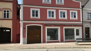 Ein rotes Gebäude mit zwei Eingangstüren, einem großen Fenster und einem kleinen Balkon.