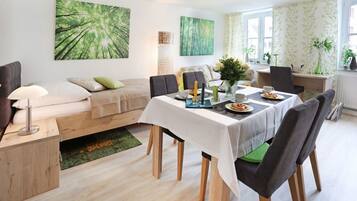 Ein modernes Wohnzimmer mit Essbereich, ausgestattet mit einer Couch, einem Couchtisch und einem Esstisch für zwei Personen.