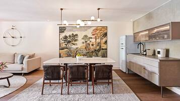 A modern living space with a dining area, kitchen, and a large abstract painting on the wall.