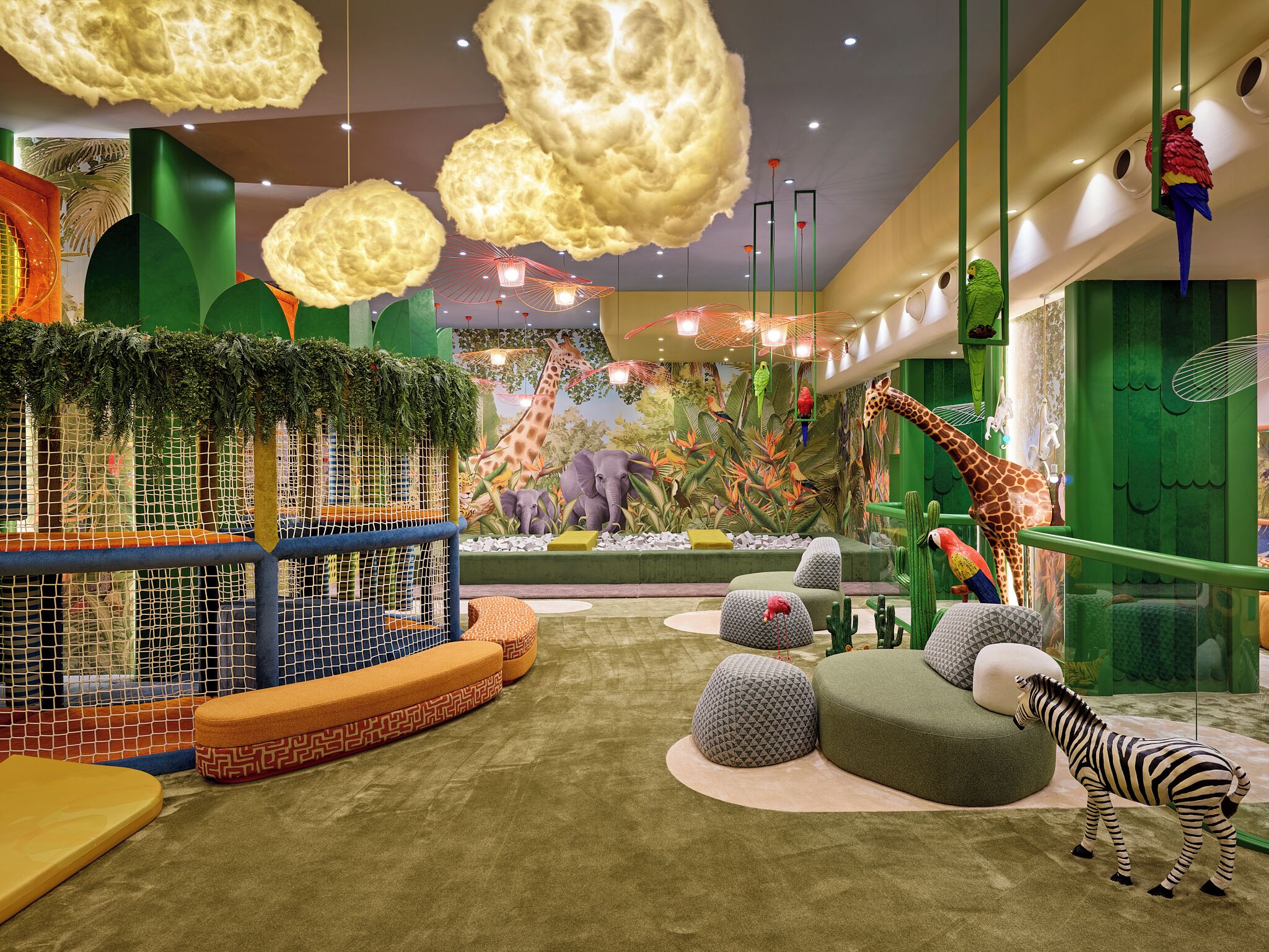 A vibrant indoor play area with a giraffe mural, a zebra, and various animal-themed furniture.
